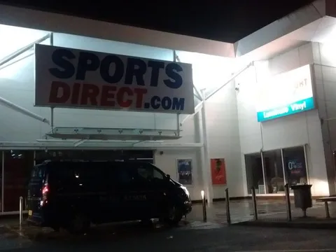 The same Sports Direct shopfront glass after commercial window cleaning, photographed at night