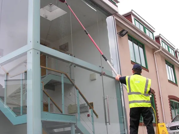 Commercial window cleaning of a glass office building with a water fed pole