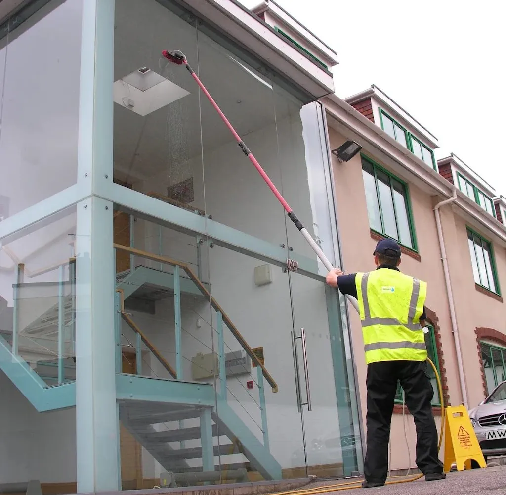 Commercial window cleaning in Surrey, a pure water pole on a glass office stairwell, the cleaner in Brilliant hi-vis