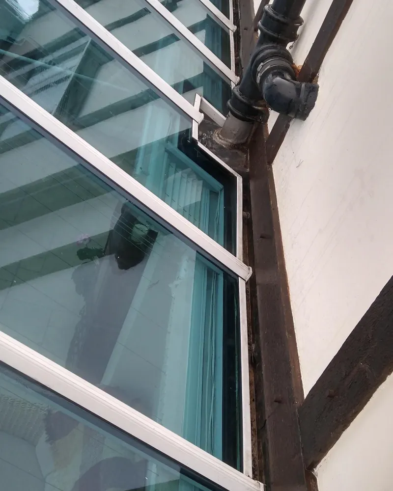 A conservatory roof gutter cleared and clean beside a cast iron downpipe