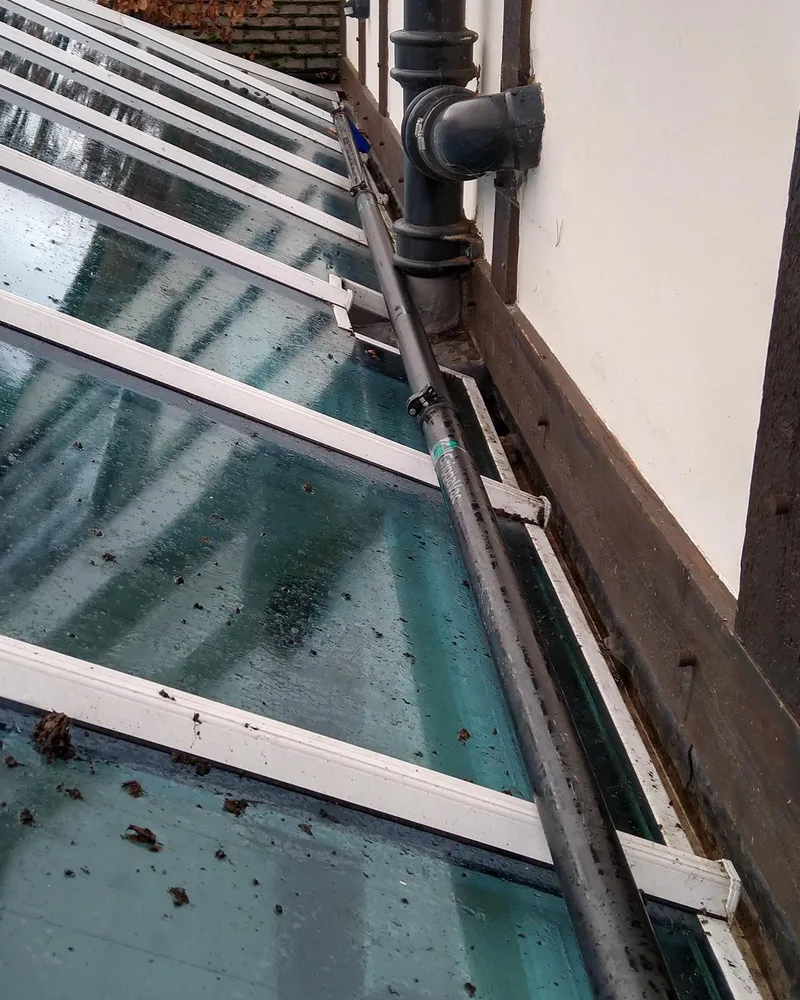 Pole clearing a conservatory gutter below a downpipe on a Guildford house