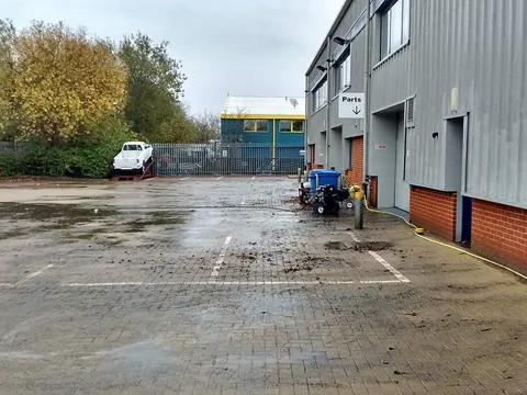 Industrial unit car park before pressure washing, block paving dark with grime and leaves