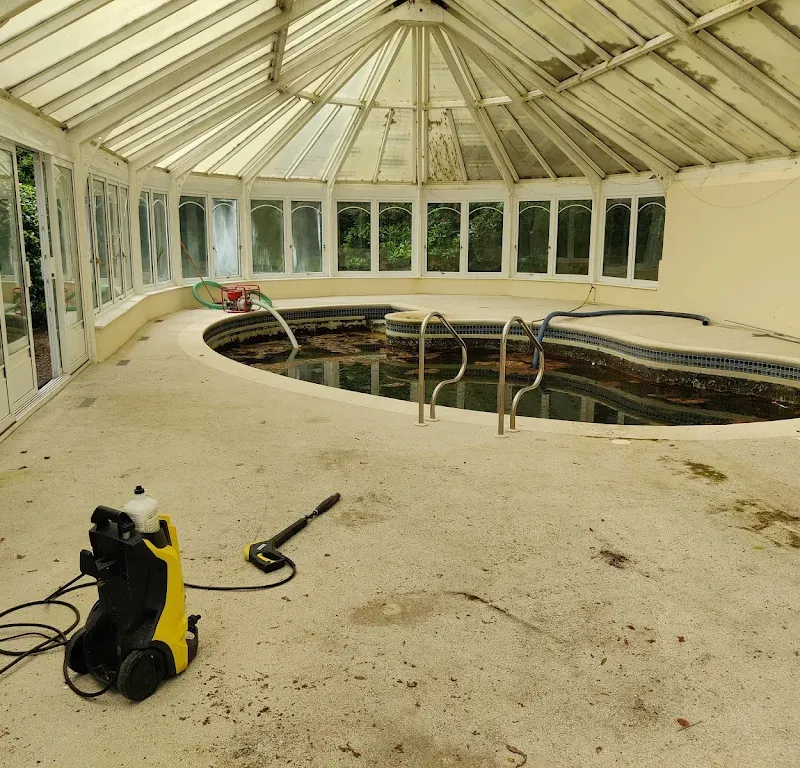 A disused indoor swimming pool full of foul water, pressure washer set up to empty and clean it