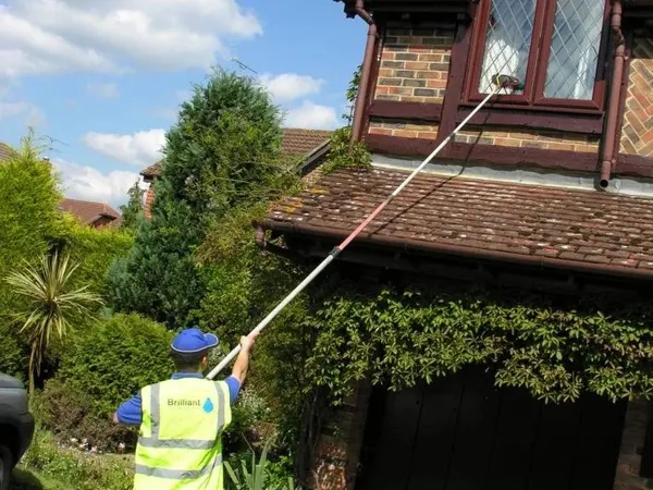 Window cleaning upstairs leaded windows with a pure water pole from the drive, cleaner in Brilliant hi-vis